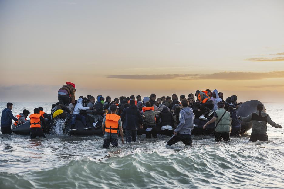 Migrants boarding a dinghy to cross the English Channel.