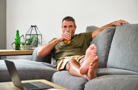 Man relaxing on a couch, drinking a beer.