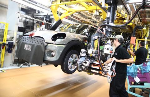 Mini Cooper assembly line worker attaching a wheel.