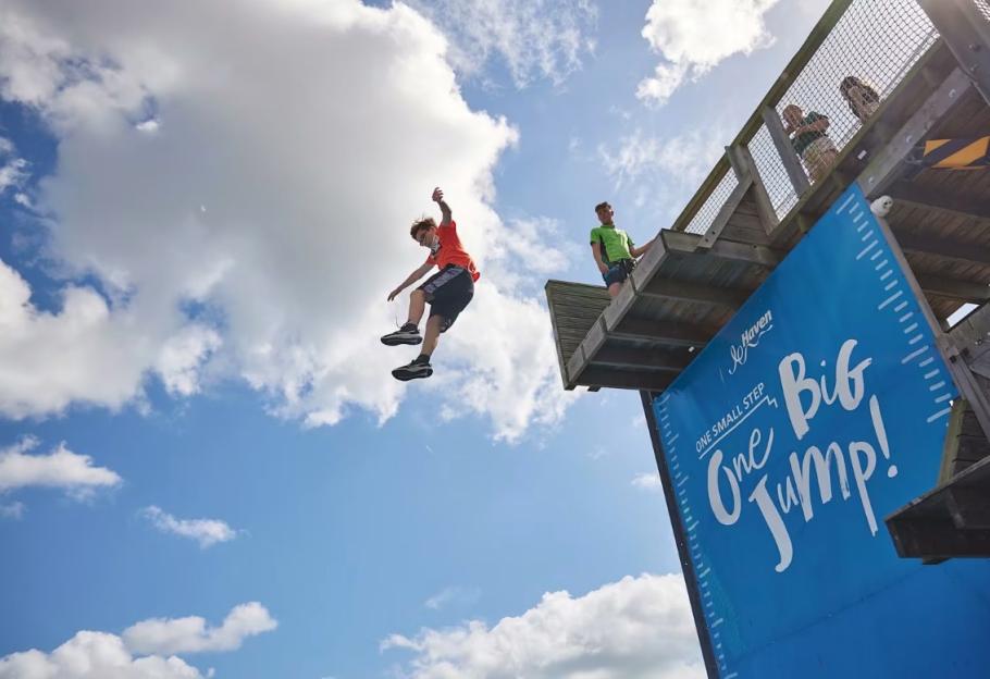 A boy jumping from a high platform into the air.