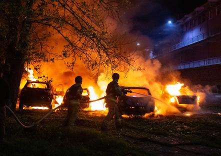 Firefighters extinguishing burning cars at night.