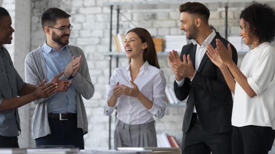 Diverse group of coworkers applauding a businesswoman.