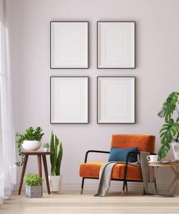 Illustration of four blank picture frames on a wall above an orange armchair in a living room.