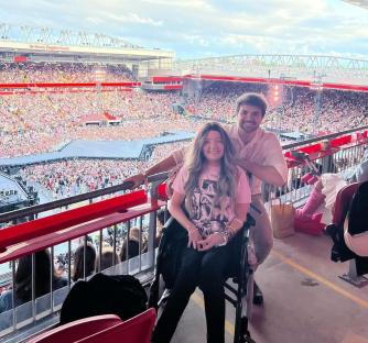Woman in wheelchair with a man at a stadium concert.