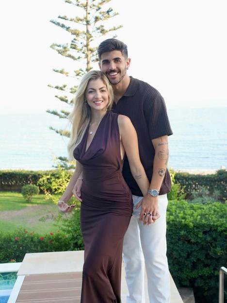 Rafaela Albino Beraldo and her partner smiling at the camera with the sea in the background.