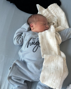 Newborn baby sleeping in blue striped pajamas.