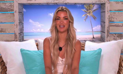 Blonde woman sitting on a wicker chair in front of a beach scene.