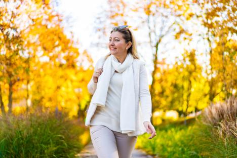 Woman walking in autumn park.