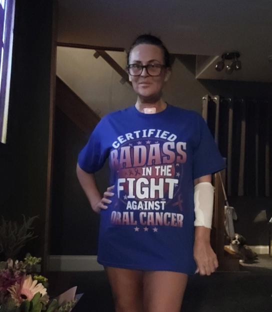 Woman wearing a "Certified Badass in the Fight Against Oral Cancer" t-shirt.