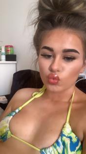 Close-up of a young woman making a kissing face while wearing a bikini top.