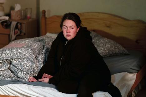 Stacey Slater from EastEnders sitting on a bed, looking upset.