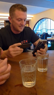 Man using phone and credit card at a restaurant table.