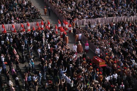 Aerial view of a large crowd taking photos of a coffin procession in St. Peter's Square.