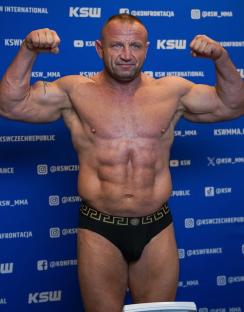 Muscular man flexing in underwear against a blue background.