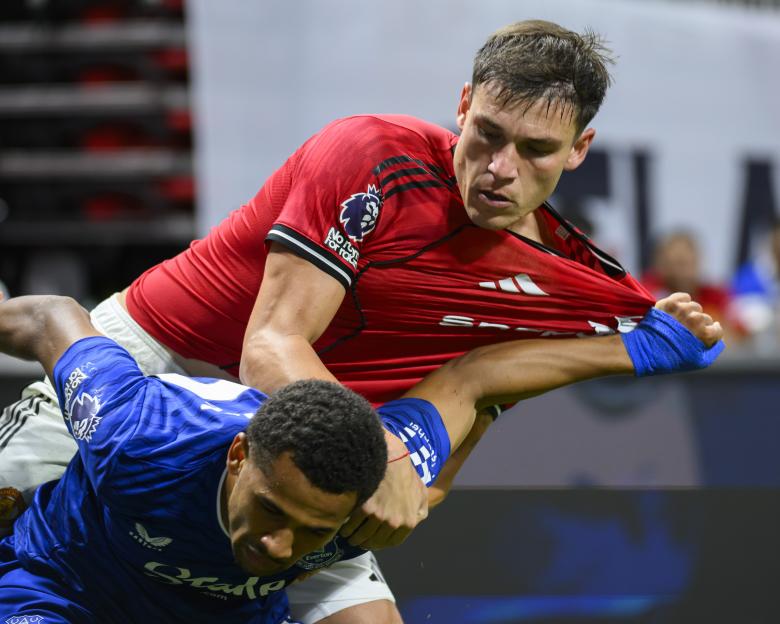 Manchester United's Manuel Ugarte wrestles with Everton's Iliman Ndiaye during a soccer match.
