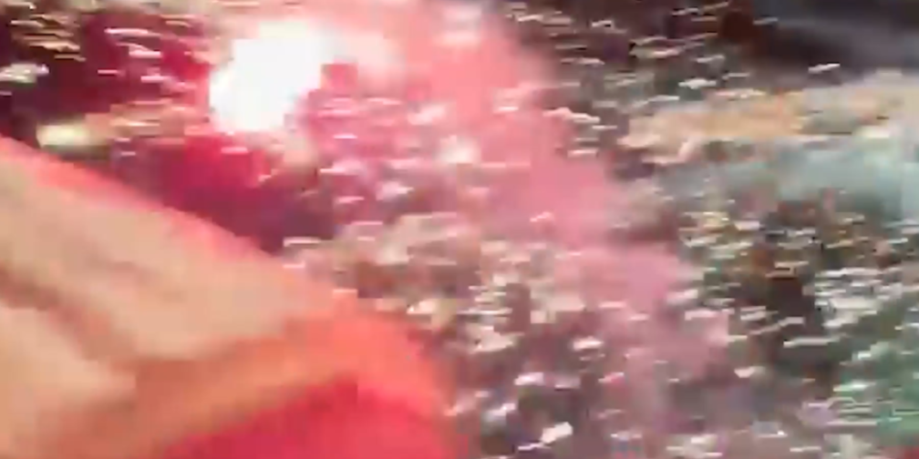 A firework with bright red light shooting into a crowd.