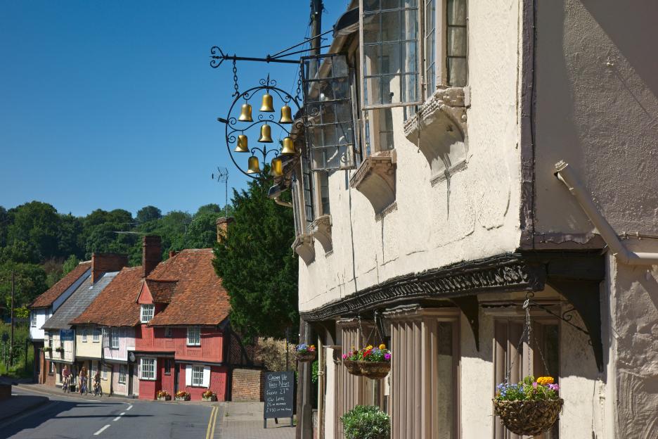 A close-up of the "Eight Bells" pub in Saffron Walden, with a decorative sign of eight golden bells hanging prominently.