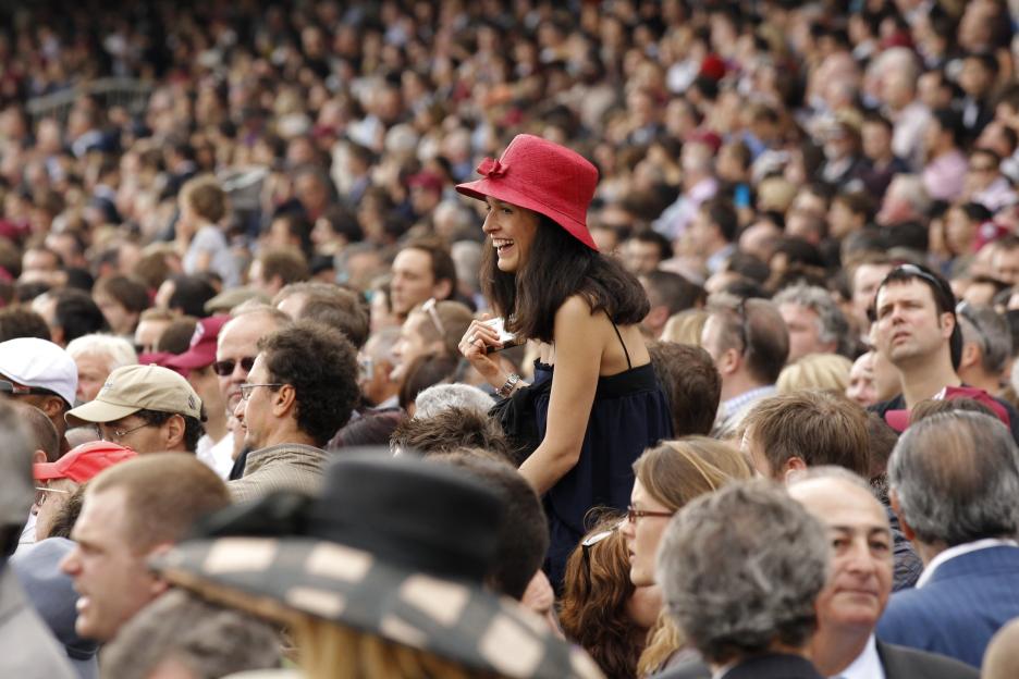 A cheerful spectator wearing a red hat at the Qatar Prix de l'Arc de Triomphe.