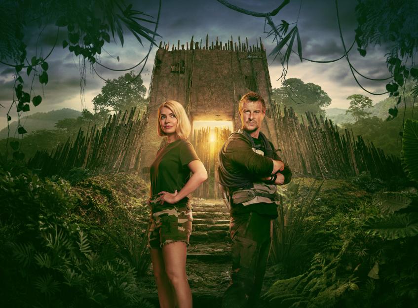 Illustration of Holly Willoughby and Bear Grylls standing in a jungle environment in front of a fort-like structure.