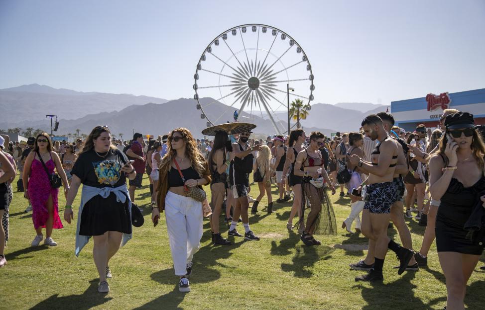 Crowds at the Coachella Music Festival in Indio, California, with a large Ferris wheel in the background.