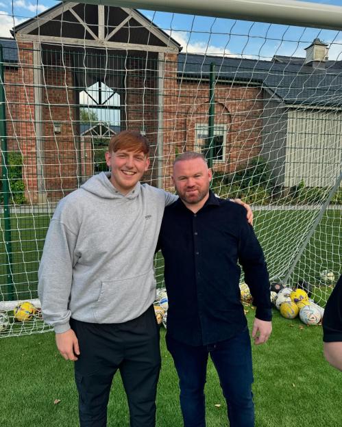 Wayne Rooney with a fan on a football field.
