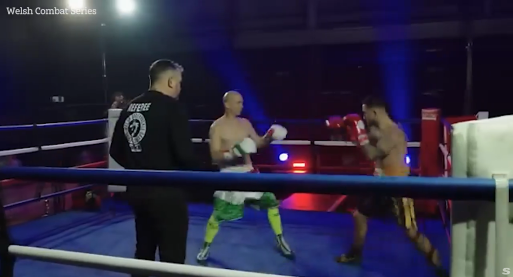 A boxing match with two boxers and a referee in the ring.