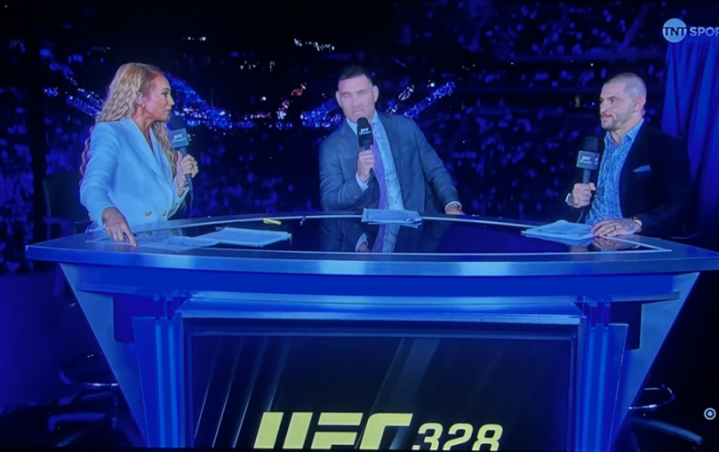 Three commentators at a desk discussing UFC 328.