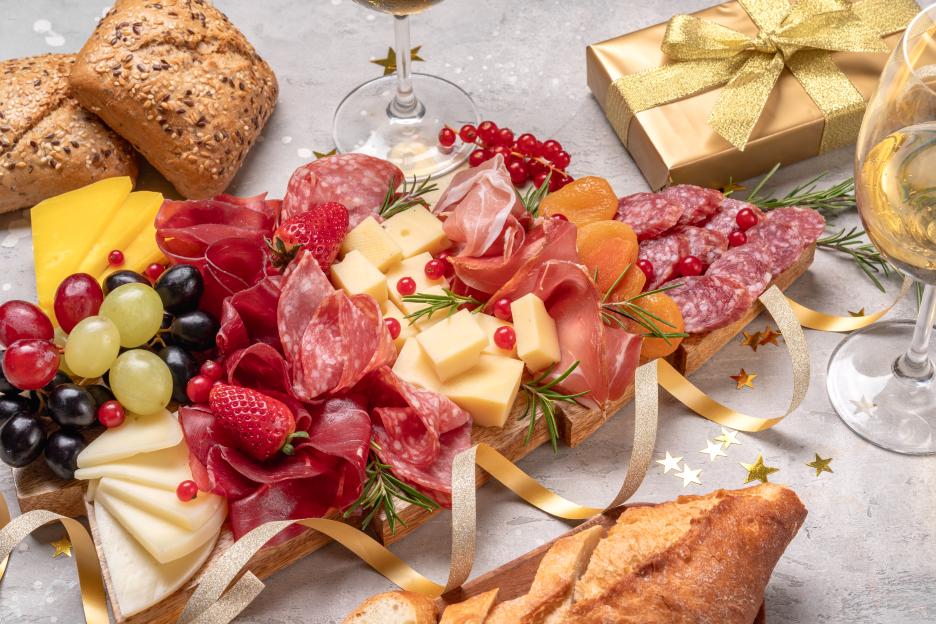 charcuterie board antipasto prosciutto ham, salami cheese and grissini served in the shape of a Christmas tree with glasses of white wine, prosecco or champagne and festive decorations