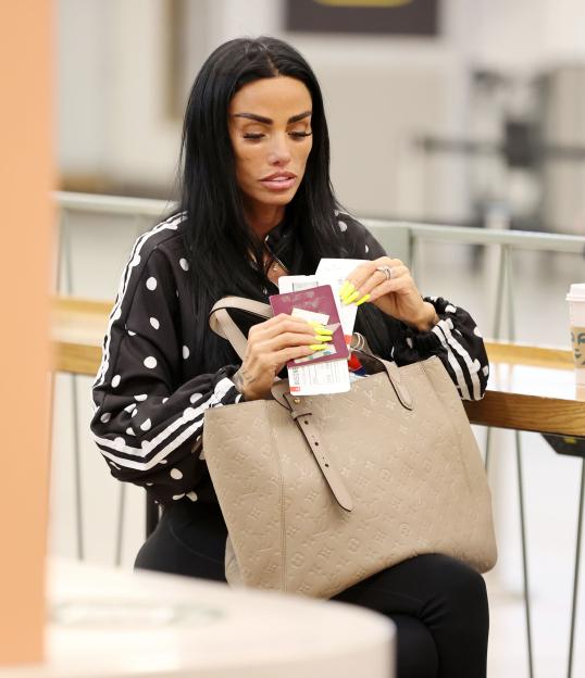 Katie Price holding her passport and boarding passes at an airport.