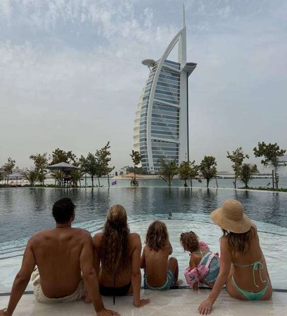Family of four sitting poolside looking at the Burj Al Arab hotel.