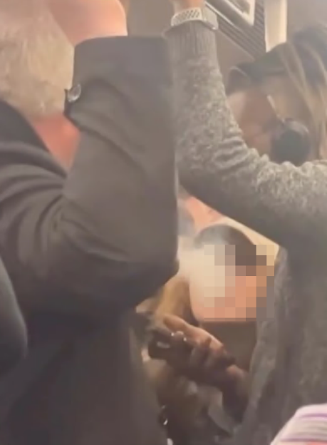 Two people in a confined space, one vaping and the other seemingly reacting to it.