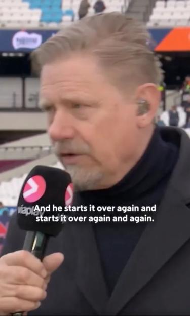 A man with a gray beard and gray hair speaking into a microphone with text overlay: "And he starts it over again and starts it over again and again."