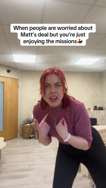 A woman with red hair and vibrant eye makeup points to herself, with a text overlay about enjoying missions while others worry about a deal.