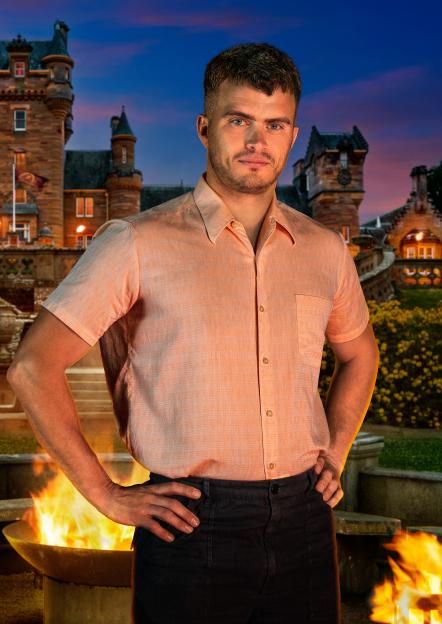 Matthew, Creative Director, standing in front of a castle with a bonfire.