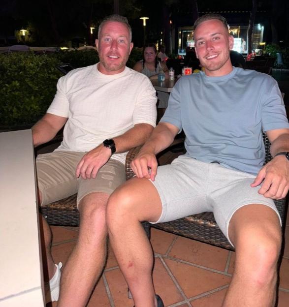 Two men sit outdoors at night, one with a scrape on his shin, indicating a fall due to his MS diagnosis.