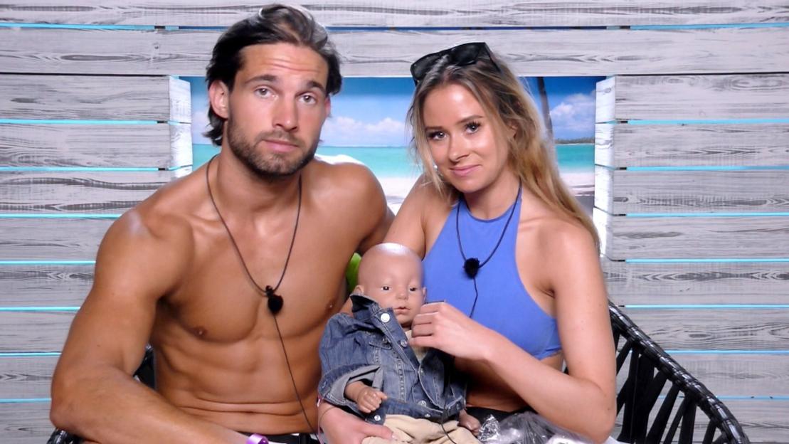 Camilla Thurlow and Jamie Jewitt posing with a baby doll during the "Love Island" TV show.