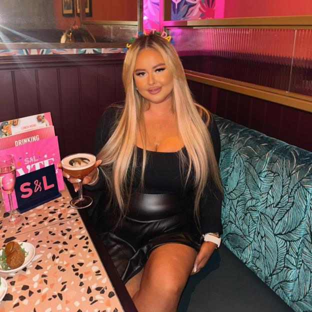 Charly Anne posing with a cocktail in a restaurant.