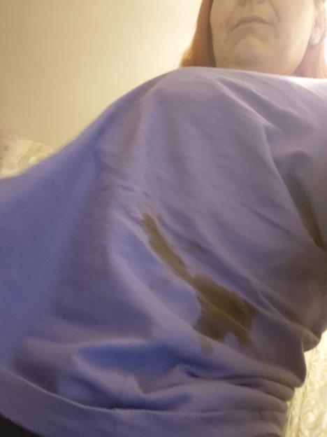 Woman wearing a light purple shirt with a dark brown stain.