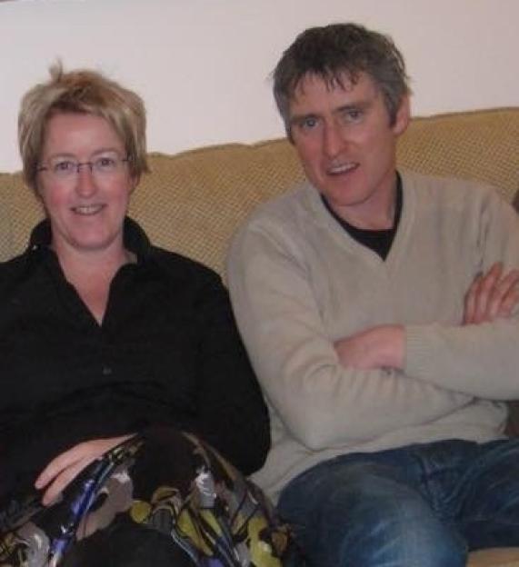 Sarah Lundy and her late husband Darren sitting on a couch.