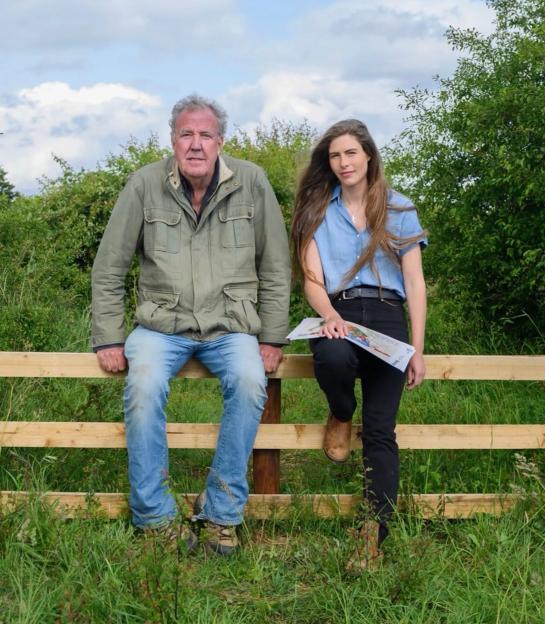 Jeremy Clarkson and Hannah Bourne-Taylor sitting on a wooden fence.