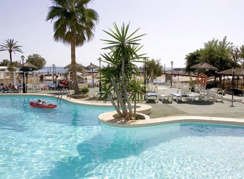 Swimming pool with a child in a red float and palm trees.
