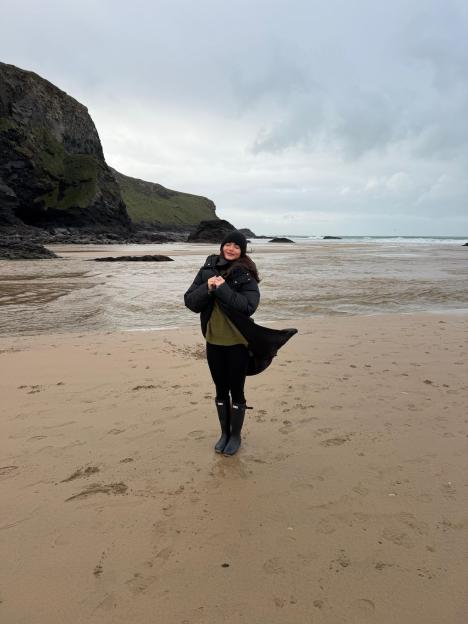 India Reynolds standing on a sandy beach wearing a winter coat and boots.
