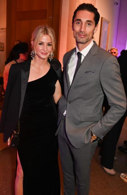 A man in a gray suit and a woman in a black velvet dress at the 'Zoë Law: Legends' Photography Exhibition at the National Portrait Gallery.