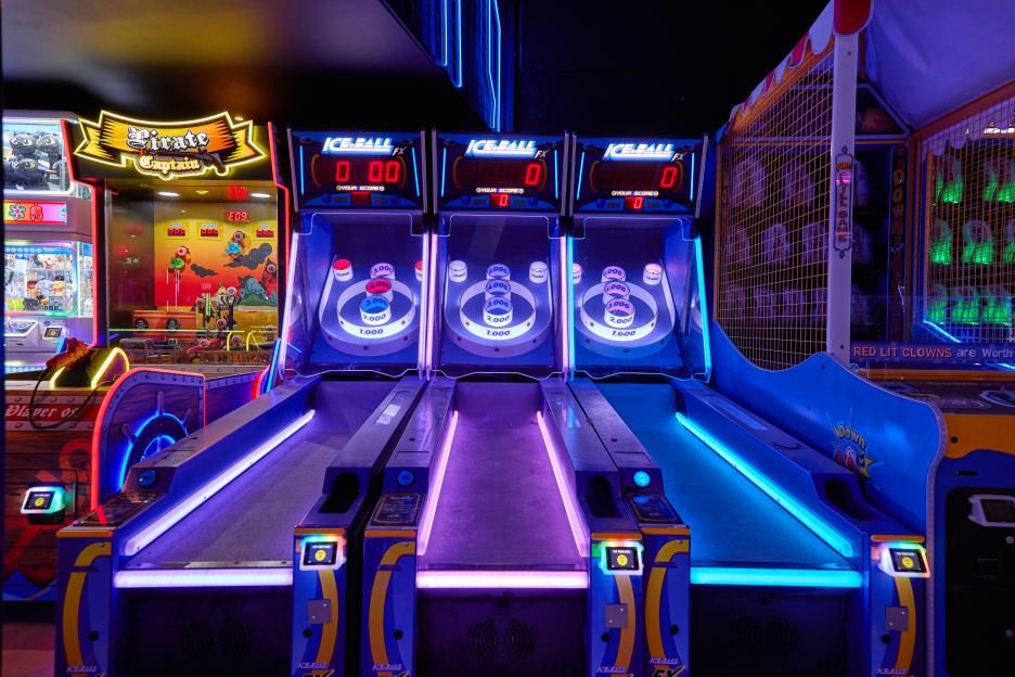 Three "Ice Ball FX" arcade games with glowing blue and purple lanes and scoreboards, next to a "Pirate Captain" game and a "Down the Clown" game.