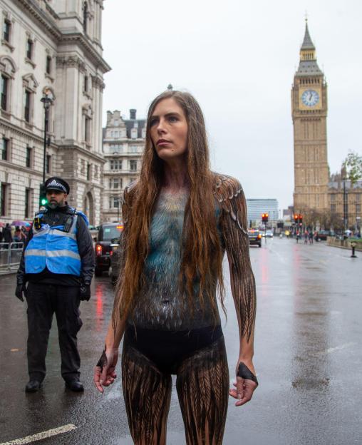 Conservationist Hannah Bourne-Taylor, body painted as a swift, marches naked on a wet street with Big Ben in the background.