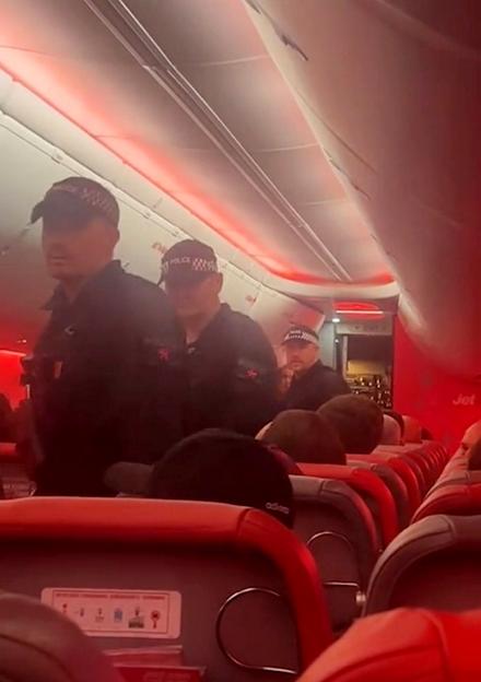 Police officers in uniform boarding a Jet2 airplane.