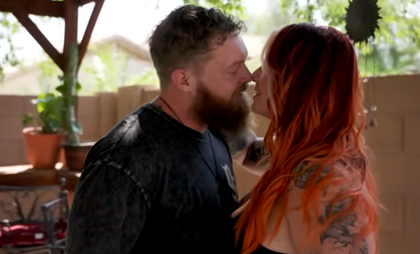 A man with a beard and a woman with red hair looking into each other's eyes, appearing as if they are about to kiss.