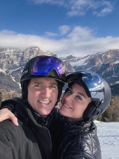 Justin Trudeau and a woman in ski helmets smiling with mountains in the background.