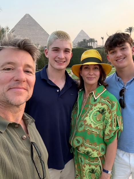 Ben Shepherd, his wife, and two sons pose for a selfie with the Pyramids of Giza in the background.