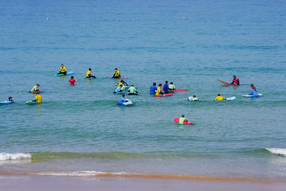 People sitting on surfboards in the water at Fistral beach, Newquay, Cornwall.